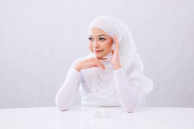 Güzel yetişkin kadın tesettürlü tesettüre yakın bir yüz beyaz arka planda izole edilmiş temiz, parlak ve parıldayan doğal Kore makyajlı bir cilde uyuyor. Sağlık ve eğitim kavramı