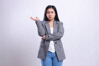 Kollarını kavuşturup sağa sunan, beyaz arka planda yalnız duran gri ceketli ve kot pantolonlu güzel bir kızın ifadesi. Reklam içeriği, moda, dergi