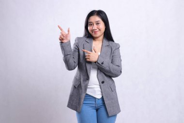 Gri takım elbiseli ve beyaz arka planda tek başına duran kot pantolonlu, iki eliyle gülümseyen güzel genç bir kadının ifadesi. Reklam içeriği, moda, afiş, dergi