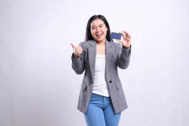 Güzel, genç ofis kızı, neşeli el işareti. Tamam. Güzel tabela ve gri takım elbiseli banka kartı üyesi beyaz arka planda tek başına duruyor. Yaşam tarzı ve aktarım için