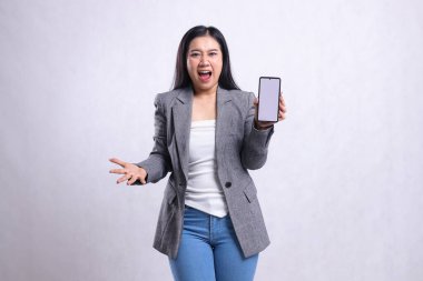 Beyaz arka planda izole edilmiş gri takım elbise giyen güzel, genç bir ofis kadınının kameraya yandan bağırışının ifadesi. Teknoloji, yaşam tarzı ve tanıtım içeriği için