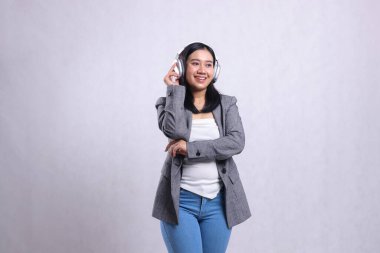 Güzel, genç bir ofis kadını, neşeli samimi kucaklaşmalar, kulaklık takmalar, müzik dinlemeler, beyaz arka planda izole edilmiş gri takım elbiseler. Yaşam tarzı, reklamcılık.