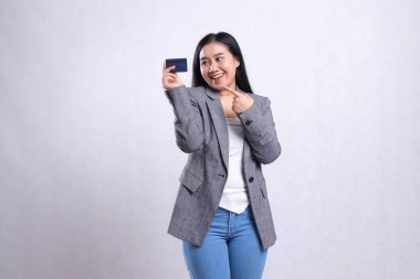 Neşeli, güzel, yetişkin bir ofis hanımı, beyaz arka planda izole bir şekilde duran gri takım elbiseli bankamatik kartı gösteriyor ve tutuyor. şirket, yaşam tarzı, finans, işlem içeriği