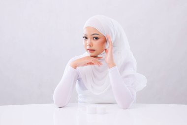 Güzel yetişkin kadın Asya 'nın zarif tesettürlü yüzü beyaz arka planda izole edilmiş temiz, parlak ve parlayan ciltli kameraya bakıyor. cilt bakımı, sağlık, eğitim