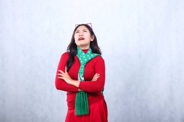 Kırmızı kazak giyen, Noel Baba şapkası ve atkısı takan, hıçkıra hıçkıra ağlayan, kollarını kafasına dolayıp, mutlu noelleri ve beyaz arka planda izole edilmiş yeni yılı kutlayan bir jest kadını.