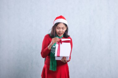 Asyalı kadın şaşırdı. Kutunun içindekiler beyaz mutlu noel kutusunu taşırken dikizliyordu. Noel partisinde süveter, Noel Baba şapkası ve eşarbı giyiyordu.