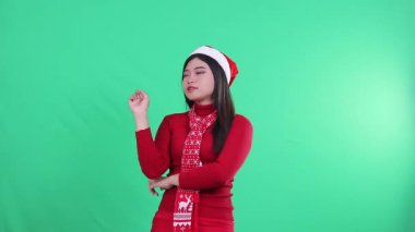 Teknoloji konsepti için kameraya bakmaktan zevk alan kızın portresi, Noel süveteri, Noel Baba şapkası ve eşarbı, yeşil arka planda izole edilmiş, yeşil ekran