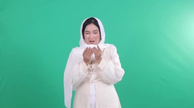 Beyaz tesettürlü bir kadın mendile hapşırıyor. Arkaplan izole edilmiş yeşil arkaplan veya yeşil ekran.
