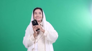 Beyaz duvak takan bir kişi, elinde tutarken bir cep telefonuna bakar, yeşil arka planda ya da yeşil ekranda izole edilmiştir.