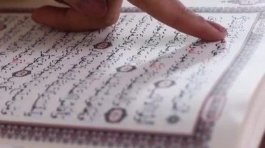 Bir insanın parmağı, Arapça, hatta Kur 'an' ı okurken açık bir kitabı işaret eder. yeşil arkaplanda ya da yeşil ekranda izole edilmiş