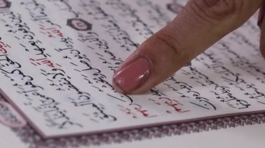 Kur 'an' ın bir sayfasını işaret eden bir parmağı kapat, Arapça reçete ile, metne ve el detaylarına odaklan, yeşil arkaplan veya yeşil ekran üzerinde izole edilmiş