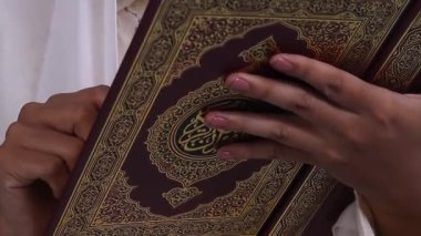 Yeşil arkaplanda veya yeşil ekranda izole edilmiş, altın dekoratif elementler ve hat tasarımı ile kahverengi Kuran 'ı tutan ellerin yakın çekimi.