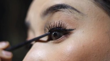 Bir kadının kirpiklerine rimel sürerken, göz makyajını göz alıcı ve şık bir görünüş için arttırırken..