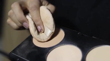 Toz temelini süngerle uygulayan bir elin yakın plan çekimi. Güzellik, kozmetik ve makyaj aletlerine odaklan. Güzellik ve cilt bakımı.