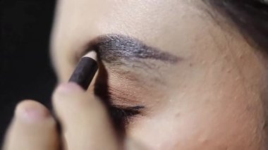 Kaşlarını şekillendirmek ve güzelleştirmek için kaş kalemi süren bir kadının yakın plan fotoğrafı. Güzellik içeriği için mükemmel.