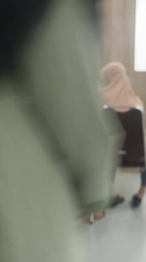 Modern bir iş ortamında kültürel çeşitliliği ve takım çalışmasını sembolize eden masa etrafında işbirliği yapan tesettürlü bir grup kadının yer aldığı odaksız bir sahne..