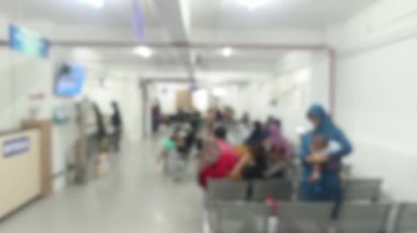 Yoğun bir hastane bekleme alanının tıbbi bakım bekleyen hastaları gösteren soyut bir görüntüsü. Bulanık görüntü anonimliği vurguluyor ve tıbbi yardımın özünü vurguluyor.