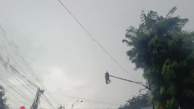 Arabanın ön camından suyla çizilmiş bir manzara kasvetli bir şehir manzarasını ortaya çıkarır. Silecek gri, bulanık şekillere karşı silueti duruyor. Yağmur damlaları ise çevreyi bozuyor..