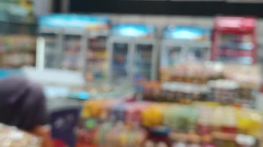 Kasıtlı olarak bulanık bir süpermarket sahnesinde alışveriş yapan, ekran ve ortam aydınlatması olan, perakende alanında bir hareket hissi yaratan.