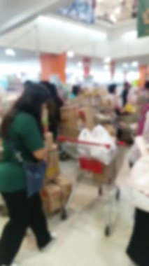 Kalabalık bir süpermarkette gezinen müşteriler günlük işlerinin özünü ve modern bir perakende sektöründeki hareketli ticaret atmosferini yakalıyorlar.