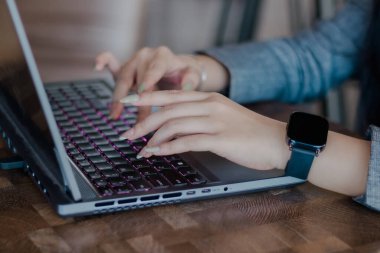 Kapalı çekimde dizüstü bilgisayarda çalışan bir kadının elleri zarif bir şekilde zarif bir klavyeye yazı yazarak şık bir akıllı seğirmeyle süslenir. Modern verimliliğin özünü yakalamak.