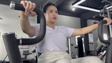 Spor salonunda egzersiz malzemesi kullanan genç bir atletik kadın. Spor aletleri. Vücut çalışıyor. Vücut geliştirme, fitness, spor ve sağlıklı yaşam tarzı konsepti. Azim ve çaba