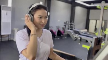 Müzik dinleyen ve koşu bandında egzersiz yapan odaklanmış bir kadın sürekli antrenman yaparak fitness hedeflerine ulaşmaya kararlı. Aktif, güçlü ve hayat dolu..
