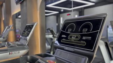 Modern bir spor salonunda sıralanmış koşu bantları genel refahı artırmak ve sağlıklı bir yaşam tarzı, spor eğitimi ve kardiyo çalışmasını desteklemek için çeşitli egzersiz seçenekleri sunuyor..