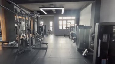 Geniş ve iyi ışıklandırılmış, çeşitli fitness ekipmanları ve makinelerin yer aldığı modern bir spor salonu. Bölge doğal güneş ışığıyla yıkanmış. Parlak ve davetkar bir çalışma alanı yaratıyor..