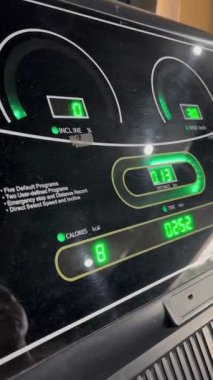 Koşu bandının egzersiz ölçümlerini gösteren yakın çekim. Hız, mesafe, eğim, zaman ve kaloriler de dahil. Dijital arayüz uygunluk sürecini aydınlatıyor.