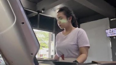 Odaklanmış genç bir kadın spor salonundaki bir koşu bandında kardiyo çalışması yapıyor, fiziksel kondisyon, aktif yaşam tarzı ve egzersiz ortamında sağlıklı alışkanlıkları teşvik ediyor..