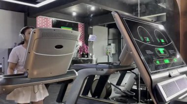 Salonda spor salonunda spor yapan birinin sergilenmesi. Fitness hedeflerine ulaşmak ve aktif bir yaşam tarzı geliştirmek için ileri teknoloji bir koşu bandı kullanıyorlar..