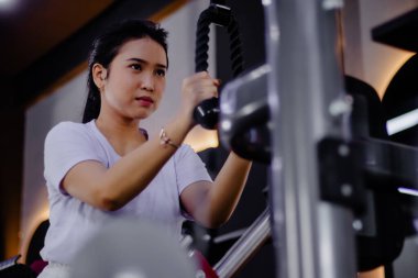 Trisepslerini halat uzatma makinesiyle çalıştıran odaklanmış bir kadının yan görüntüsü. Spor salonunda özenle ve kararlı bir şekilde egzersiz yapıyor, sağlığını geliştiriyor..