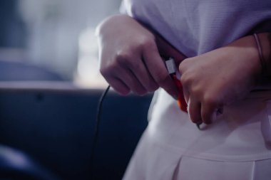 Yakın plan çekimde, elektrik ve kullanılabilirliği koruma görevine odaklanarak, elektronik şarj cihazını bir cihaza özenle bağlayan kişinin elleri vurgulanır..