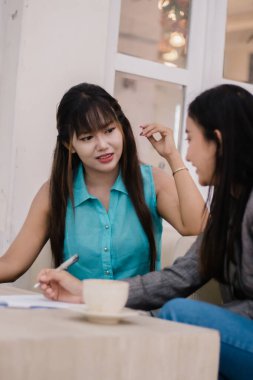İki genç iş kadını samimi bir kafede bir toplantı sırasında dostça bir tartışmaya giriştiler. Fikirlerini paylaşıyorlar, planlıyorlar ve birlikte çalışıyorlar..