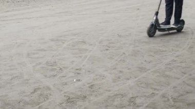 Elektrikli scooter sürerken yakalandı. Bir insan toprak yolda kısa bir yolculuk için scooter kullanır. Bu kişisel kentsel hareketlilik ve ekolojik bilinci gösteriyor.