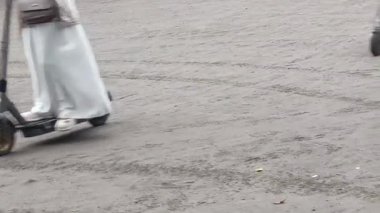 Elektrikli scooter sürerken yakalandı. Bir insan toprak yolda kısa bir yolculuk için scooter kullanır. Bu kişisel kentsel hareketlilik ve ekolojik bilinci gösteriyor.