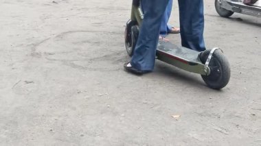 Elektrikli scooter sürerken yakalandı. Bir insan toprak yolda kısa bir yolculuk için scooter kullanır. Bu kişisel kentsel hareketlilik ve ekolojik bilinci gösteriyor.