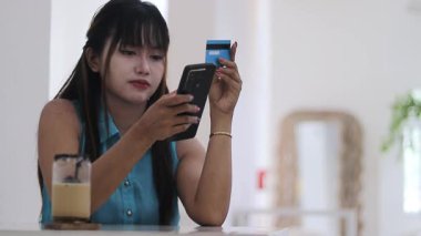 Akıllı telefonu ve kredi kartıyla online alışveriş yapan genç bir kadın. E-ticaret ve dijital mali işlemlerin kolaylığını yakalamak.