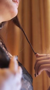 Bir kadın tarafından gösterilen hassas saç bakımı rutini, tek bir ipliğe ürün uygulamak, titiz bir şekilde...