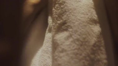 Manevi açıdan, bir kadın altın saat aydınlatması ve teşhirciliğiyle kendini yumuşak, beyaz bir havluyla nazikçe kurutur.