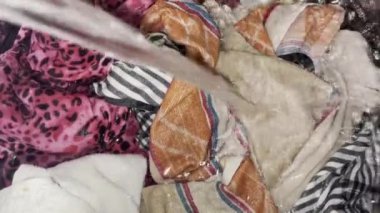 Çamaşır makinesinin içindeki kıyafetlerin üzerindeki borudan akan su.