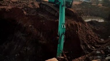Ön çapa yükleyicisi istenmeyen durgun suyu temizlemek için yerden enkazı alıyor.