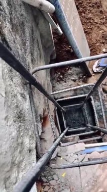 Ayakta duran çelik kolonların deliklerine ıslak beton döşüyorlar.