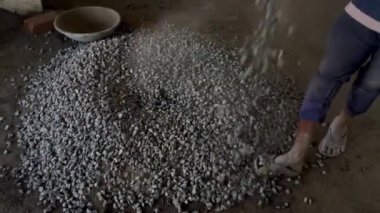 Mason worker putting down the crushed stones in a circular form to mix it with cement later on