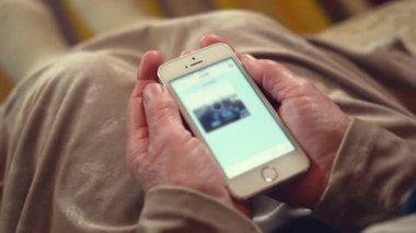 Kırışık arka planda modern aletleri tutan yaşlı bir kadının buruşuk elleri. Emekliye ayrılan kişi akıllı telefondan fotoğraf yüklemesini bekliyor.