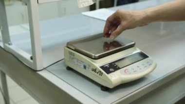 KYIV, UKRAINE - 27 Eylül 2021: Laboratuvarda elektronik ölçekte kullanılan kırmızı termal çamaşır makinesinin ağırlığı. Polimer üretim tesisinde bitmiş ürünlerin fiziksel özellikleri kontrol ediliyor