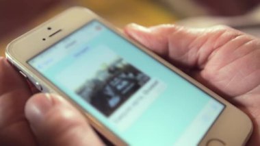 Emeklinin arka planında modern akıllı telefonu var. Son derece yakın görüşlü yaşlı bir kadının kırışık ellerinde elektronik cihaz