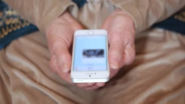 年长的母亲看着儿子通过现代智能手机聊天时的照片 握着小玩意的老年妇女擦拭过的手 — 图库视频影像