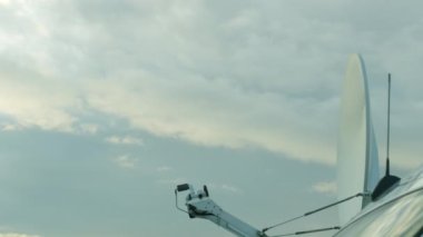 SNG araçları, bulutlu gökyüzüne karşı beyaz yuvarlak uydu ile televizyon yayınları için. Uydu canlı yayın sinyali gönderiyor.